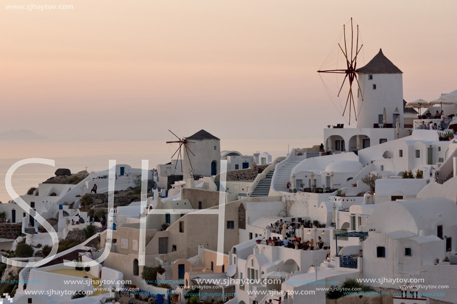 Amazing Sunset over white windmills in  town of Oia and panorama to Santorini island, Thira, Cyclades, Greece