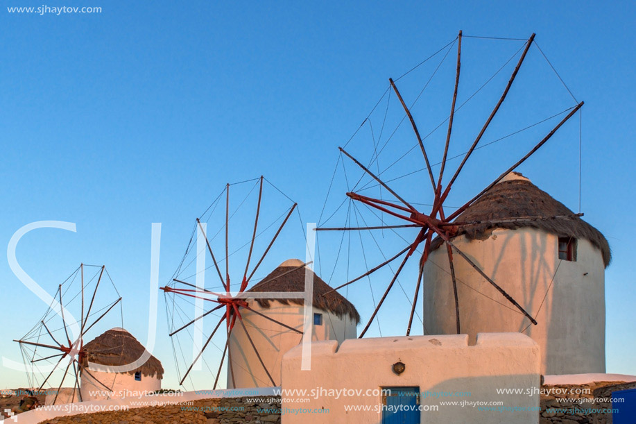 The last rays of the sun over White windmills on the island of Mykonos, Cyclades, Greece