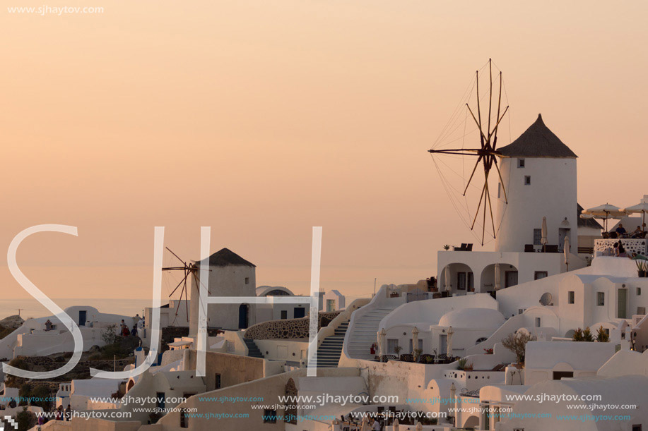 Amazing Sunset over white windmills in  town of Oia and panorama to Santorini island, Thira, Cyclades, Greece