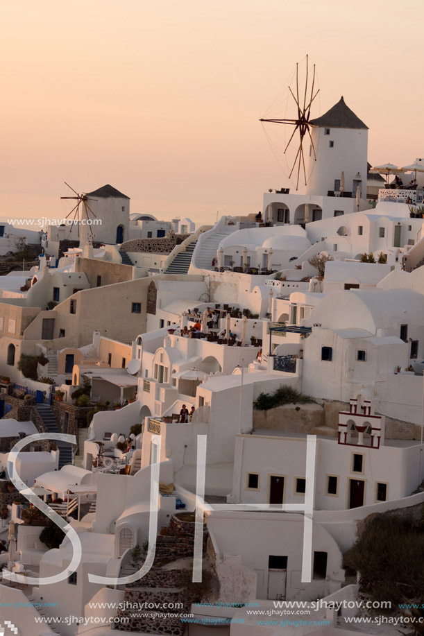 Amazing Sunset over white windmills in  town of Oia and panorama to Santorini island, Thira, Cyclades, Greece