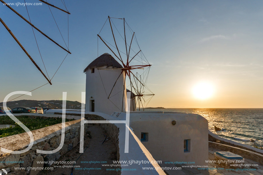 The last rays of the sun over White windmills on the island of Mykonos, Cyclades, Greece