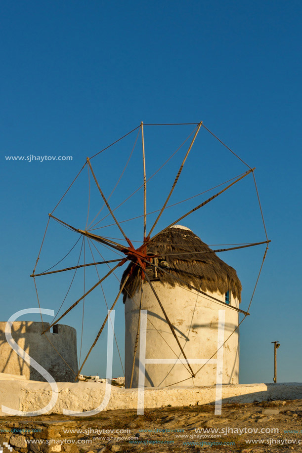 The last rays of the sun over White windmills on the island of Mykonos, Cyclades, Greece