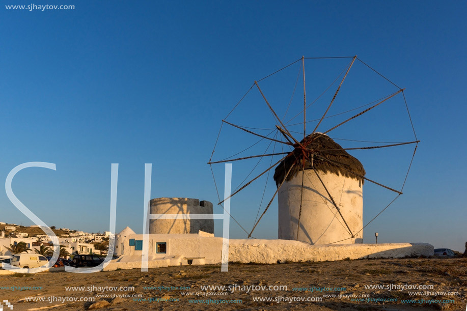 The last rays of the sun over White windmills on the island of Mykonos, Cyclades, Greece