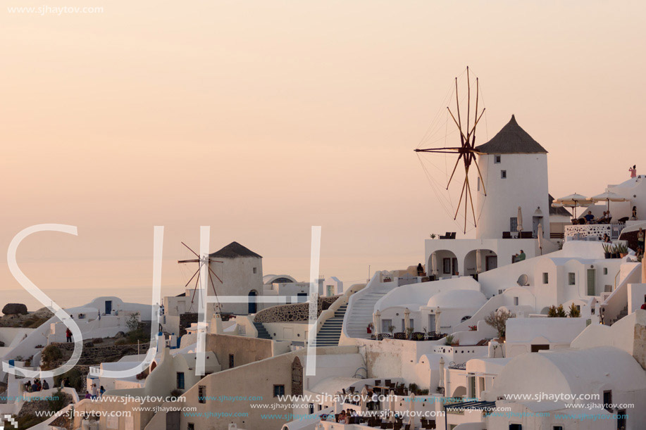 Amazing Sunset over white windmills in  town of Oia and panorama to Santorini island, Thira, Cyclades, Greece