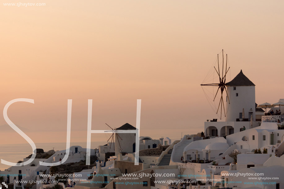 Amazing Sunset over white windmills in  town of Oia and panorama to Santorini island, Thira, Cyclades, Greece