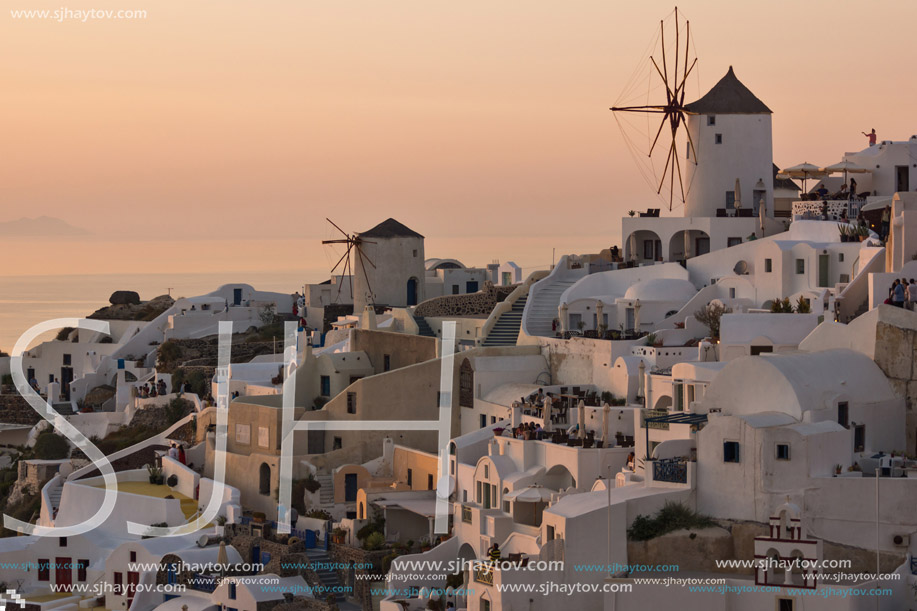Sunset panorama over white windmills in  town of Oia and panorama to Santorini island, Thira, Cyclades, Greece