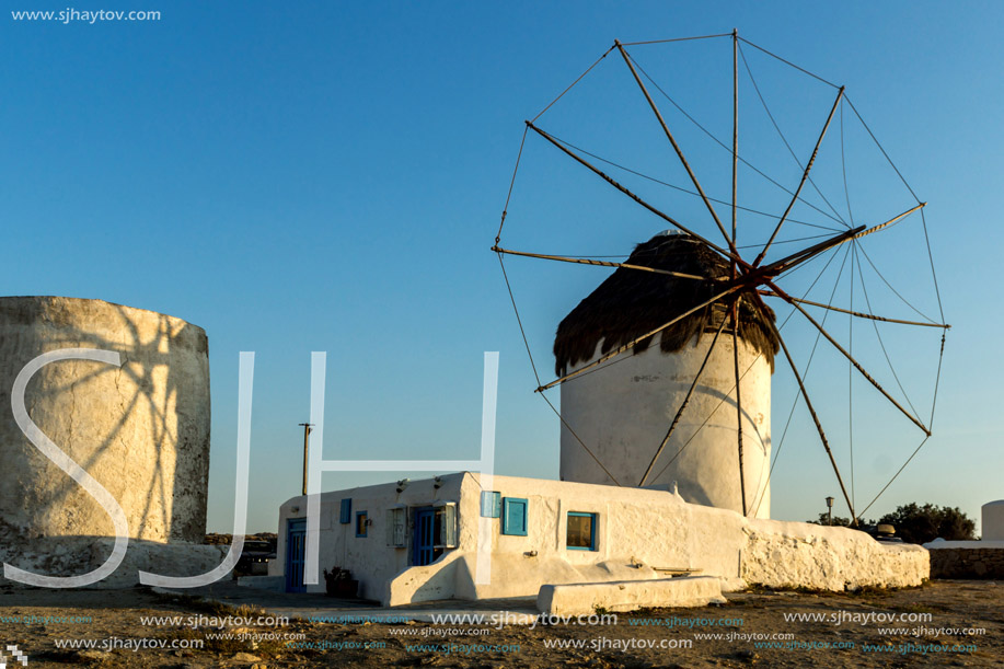 The last rays of the sun over White windmills on the island of Mykonos, Cyclades, Greece