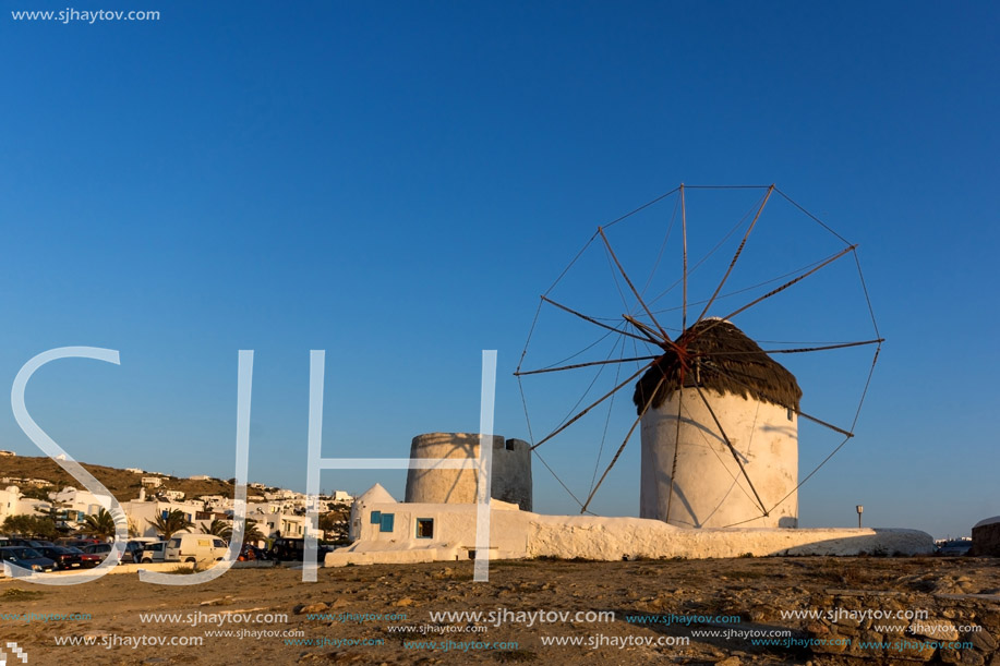 The last rays of the sun over White windmills on the island of Mykonos, Cyclades, Greece