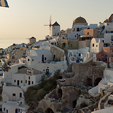 Sunset over white windmills in  town of Oia and panorama to Santorini island, Thira, Cyclades, Greece