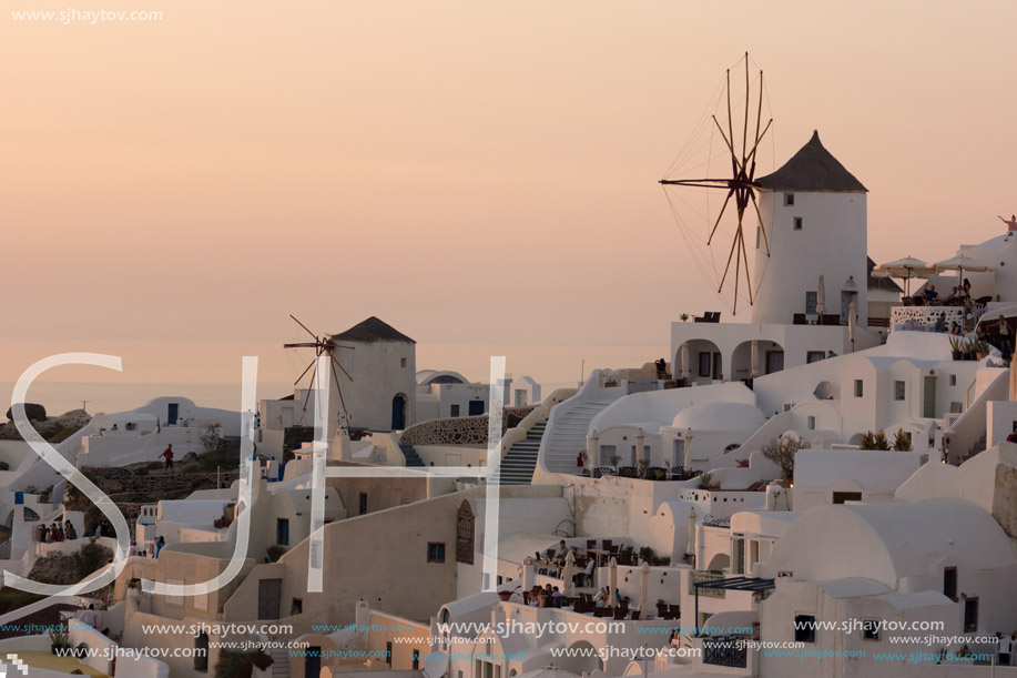 Amazing Sunset over white windmills in  town of Oia and panorama to Santorini island, Thira, Cyclades, Greece