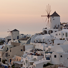 Amazing Sunset over white windmills in  town of Oia and panorama to Santorini island, Thira, Cyclades, Greece